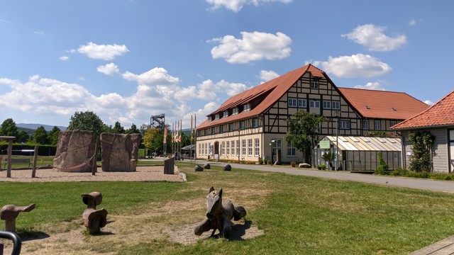 Restaurant im Bürgerpark Wernigerode mit einem Spielplatz im Vordergrund und einem Aussichtsturm im Hintergrund.