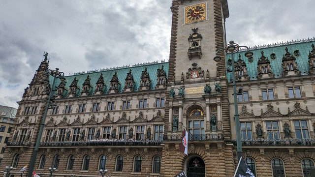 Am Rathaus von Hamburg hängt eine Fahne mit dem Vereinslogo des FC St. Pauli. Auf dem Balkon steht die Mannschaft.